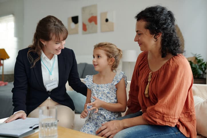 Social worker talking to child while visiting a family at home.