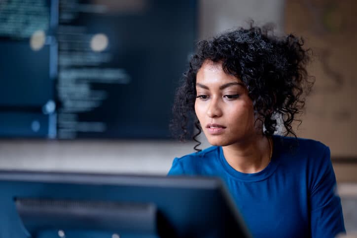 A female business analyst reviewing data on a computer in a tech business office.