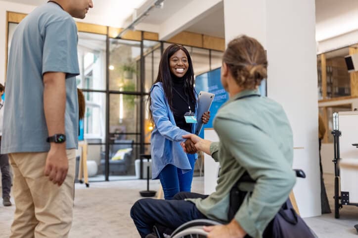 Black female business professional meeting a colleague in a wheelchair at a business conference.