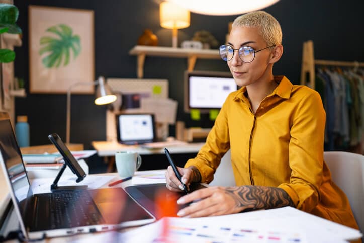 Female graphic designer working on her tablet device in her home office.