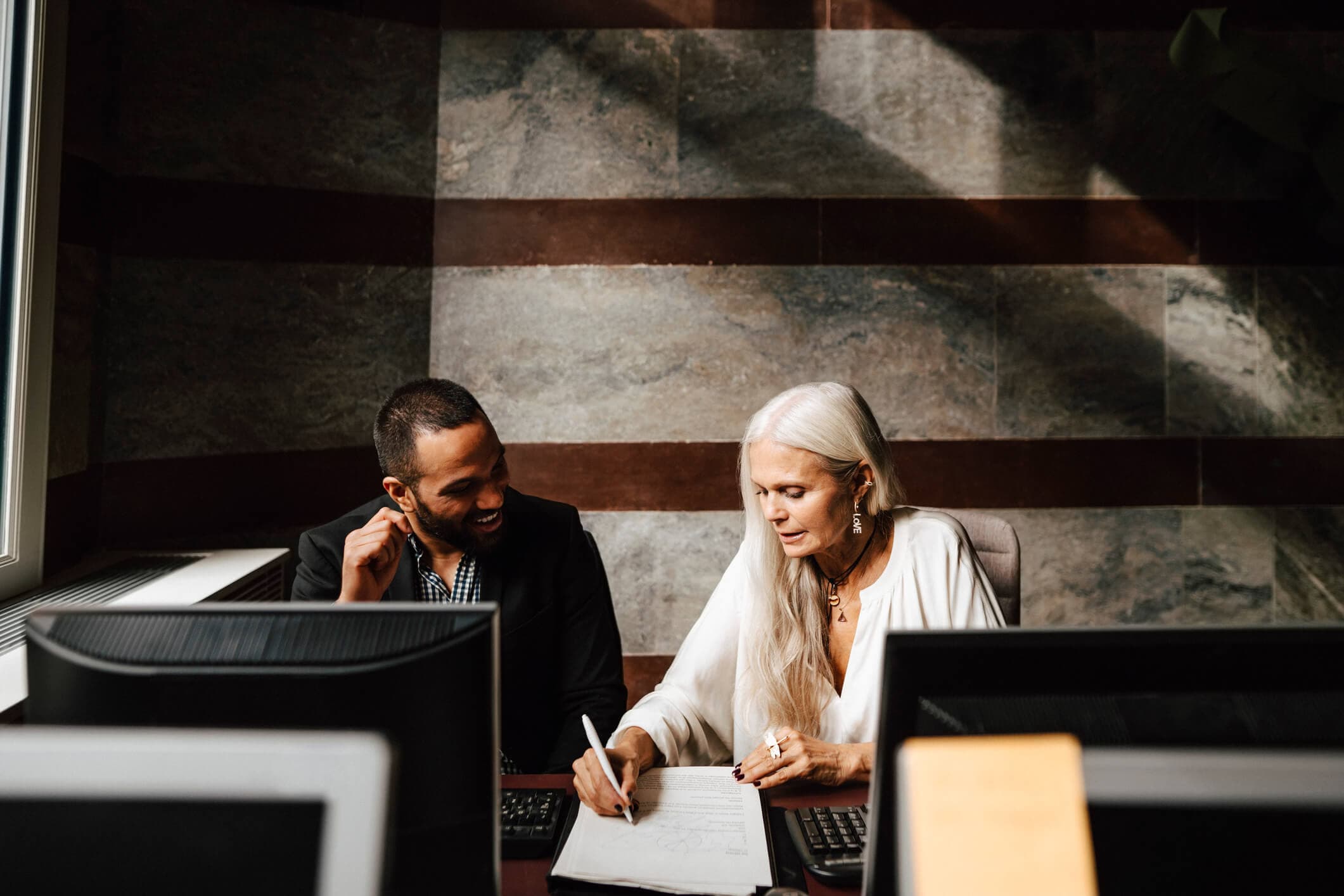 Senior female lawyer discussing a contract with a junior male legal assistant at the office.
