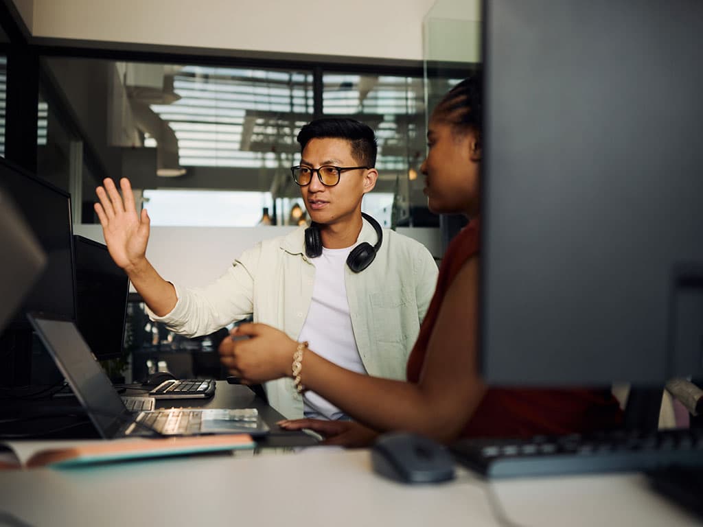 Programmers working together on a computer in office discussing a project.