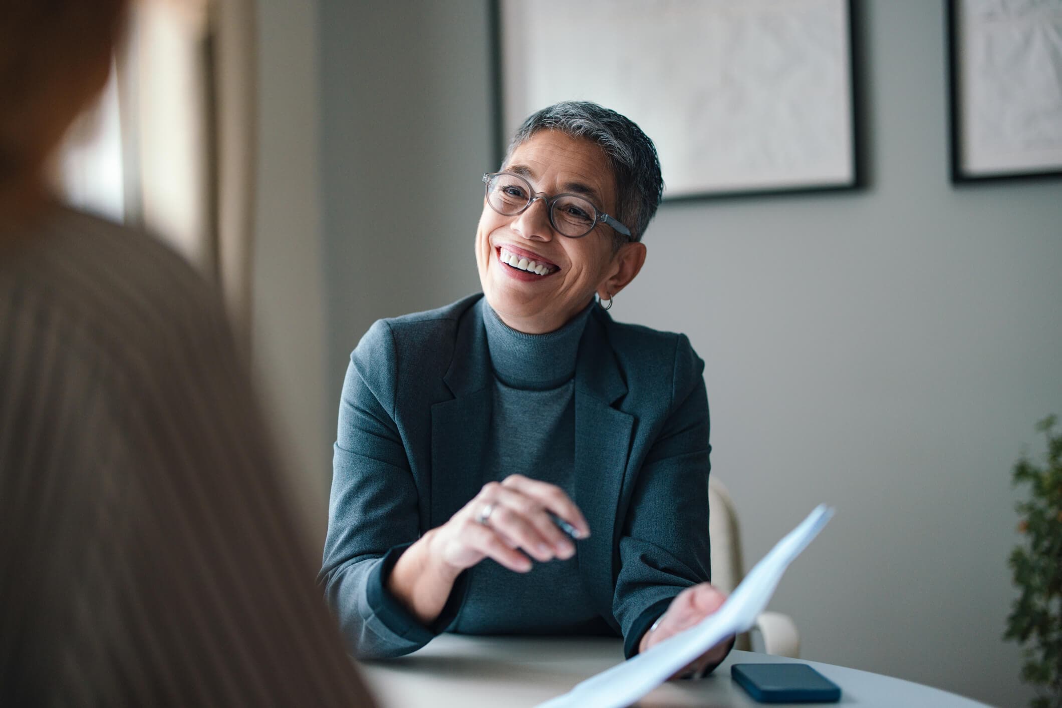 Senior female financial accountant smiling during a business conversation in a modern office setting.