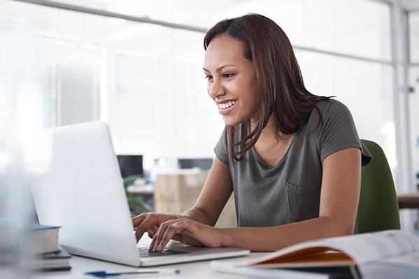 A woman smiling warmly at her laptop screen