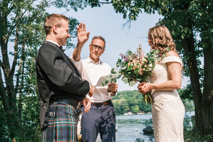 Bride and groom and wedding officiant during outdoor wedding ceremony