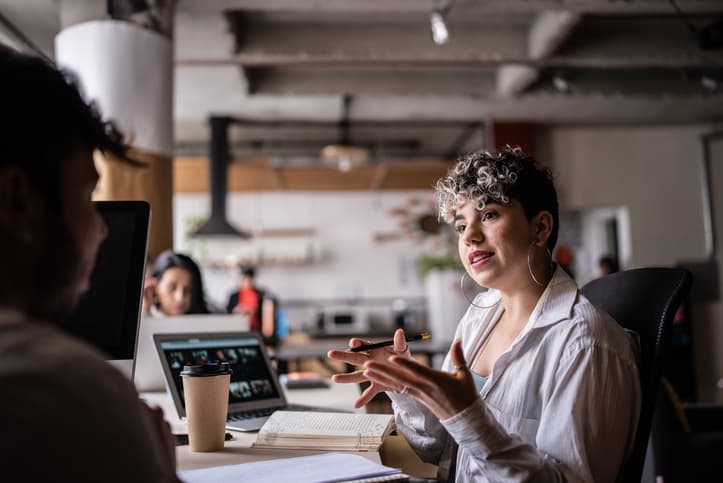 Project manager chatting about priorities with a colleague in the office.
