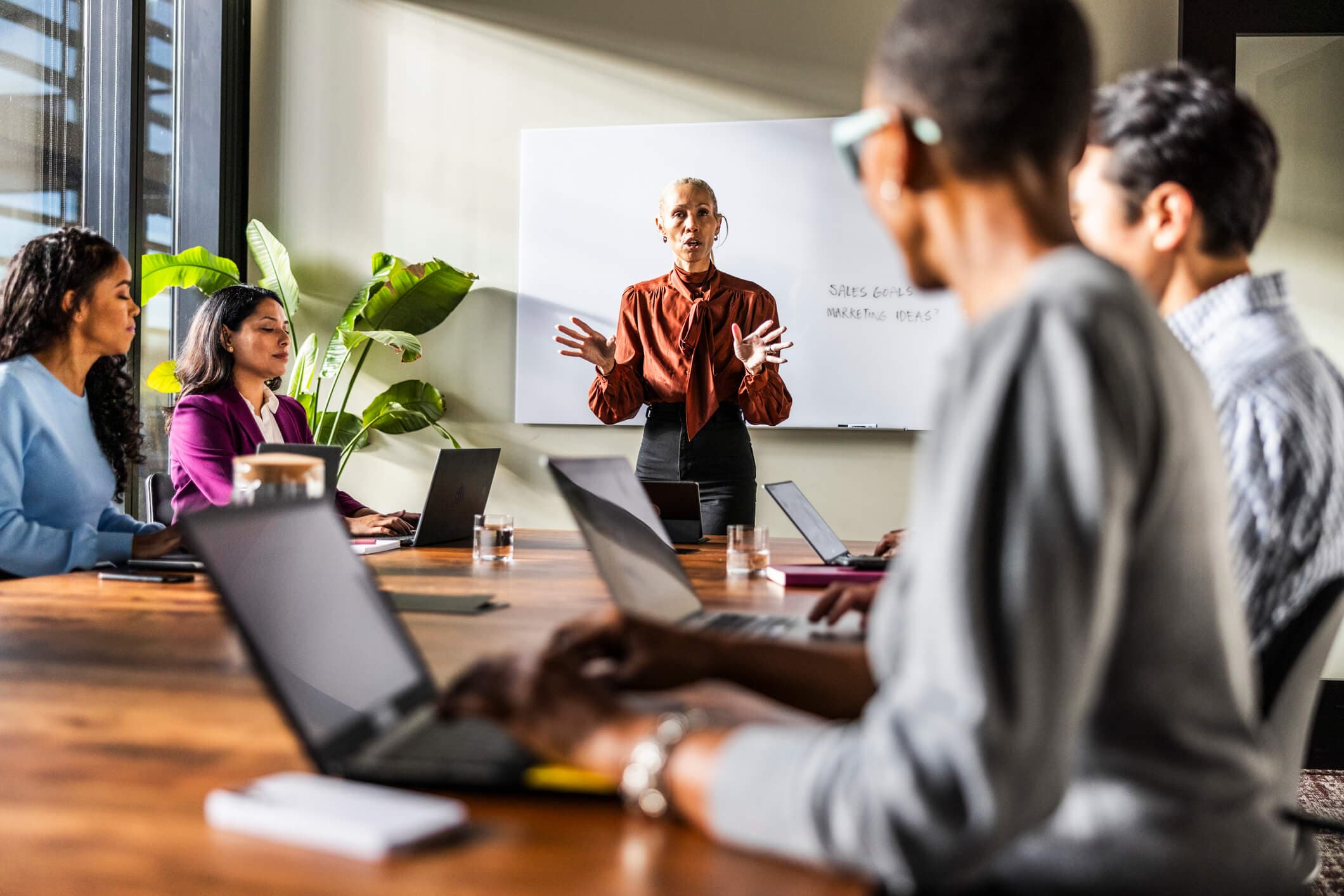Female business owner speaking to office workers in a modern conference room.