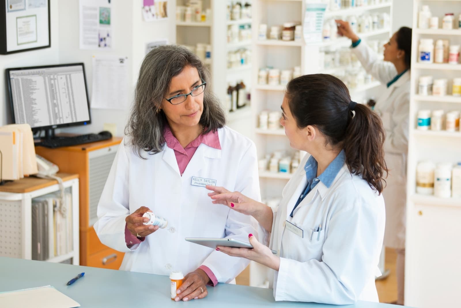 Two women in lab coats talking.
