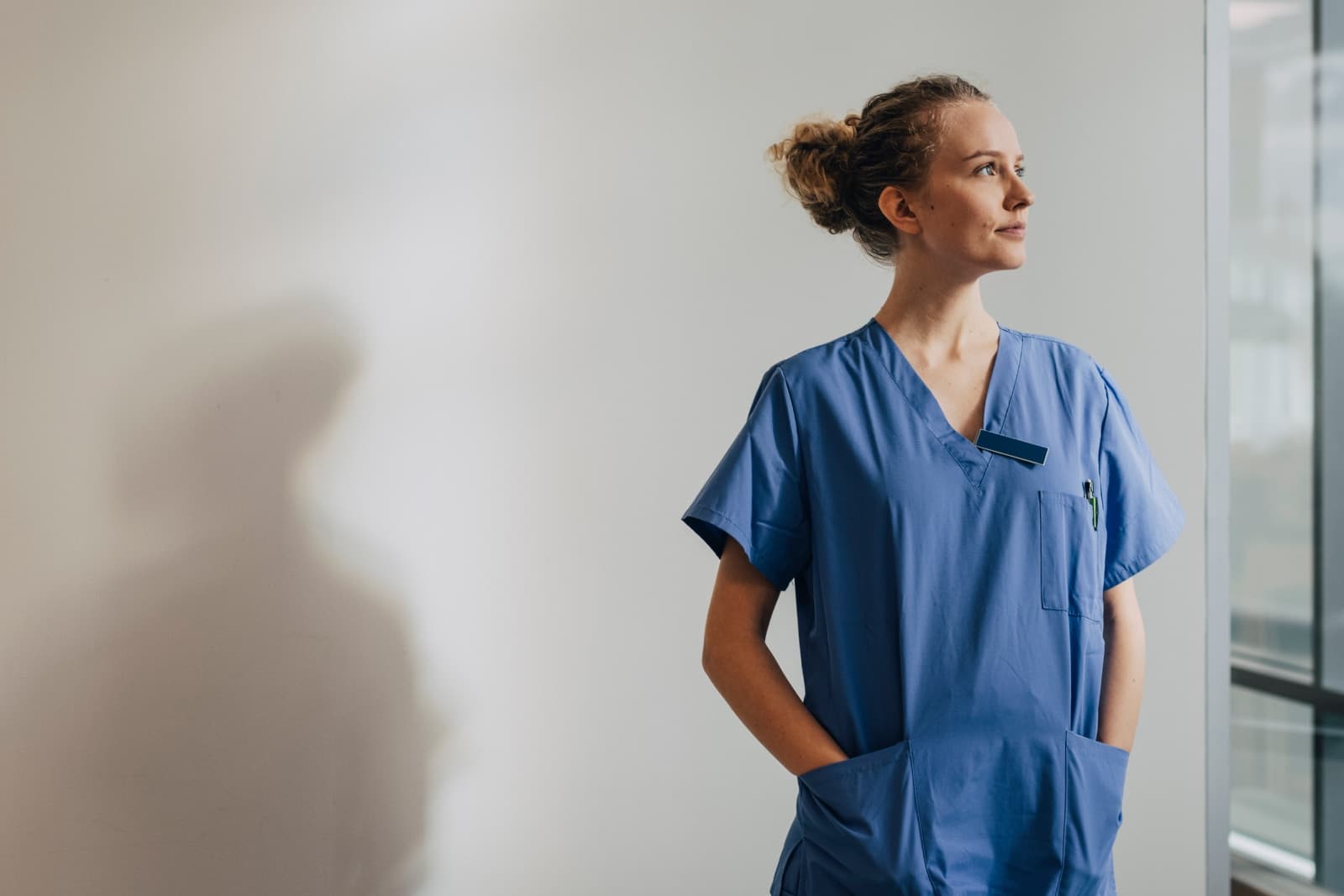 woman looking upwards with hand in her scrub pockets.