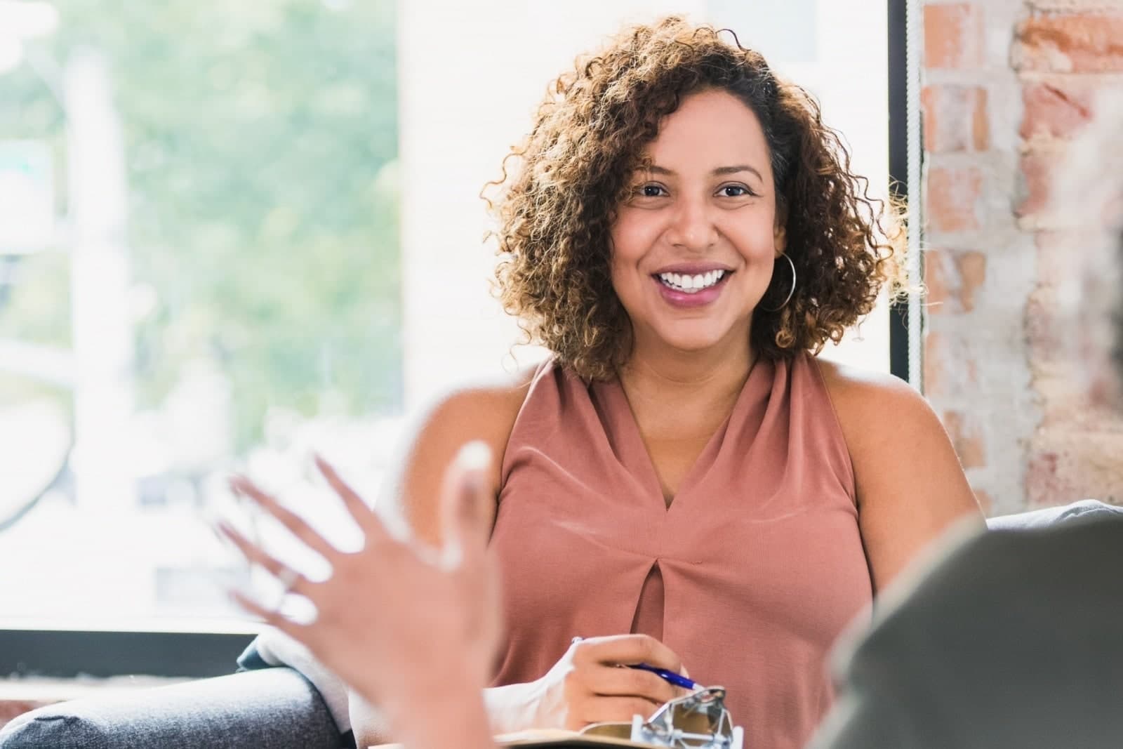Woman smiling at a person with their hand raised.